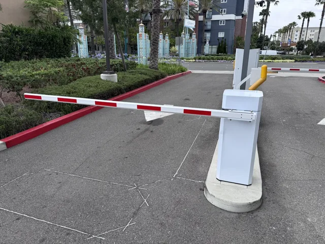Detail of the pivot mechanism and arm attachment on a parking barrier gate operator and housing. The horizontal arm connects to a motorized housing mounted at lane level. Self-Storage Equipment Checklist: The Re-Check Routine After Opening
